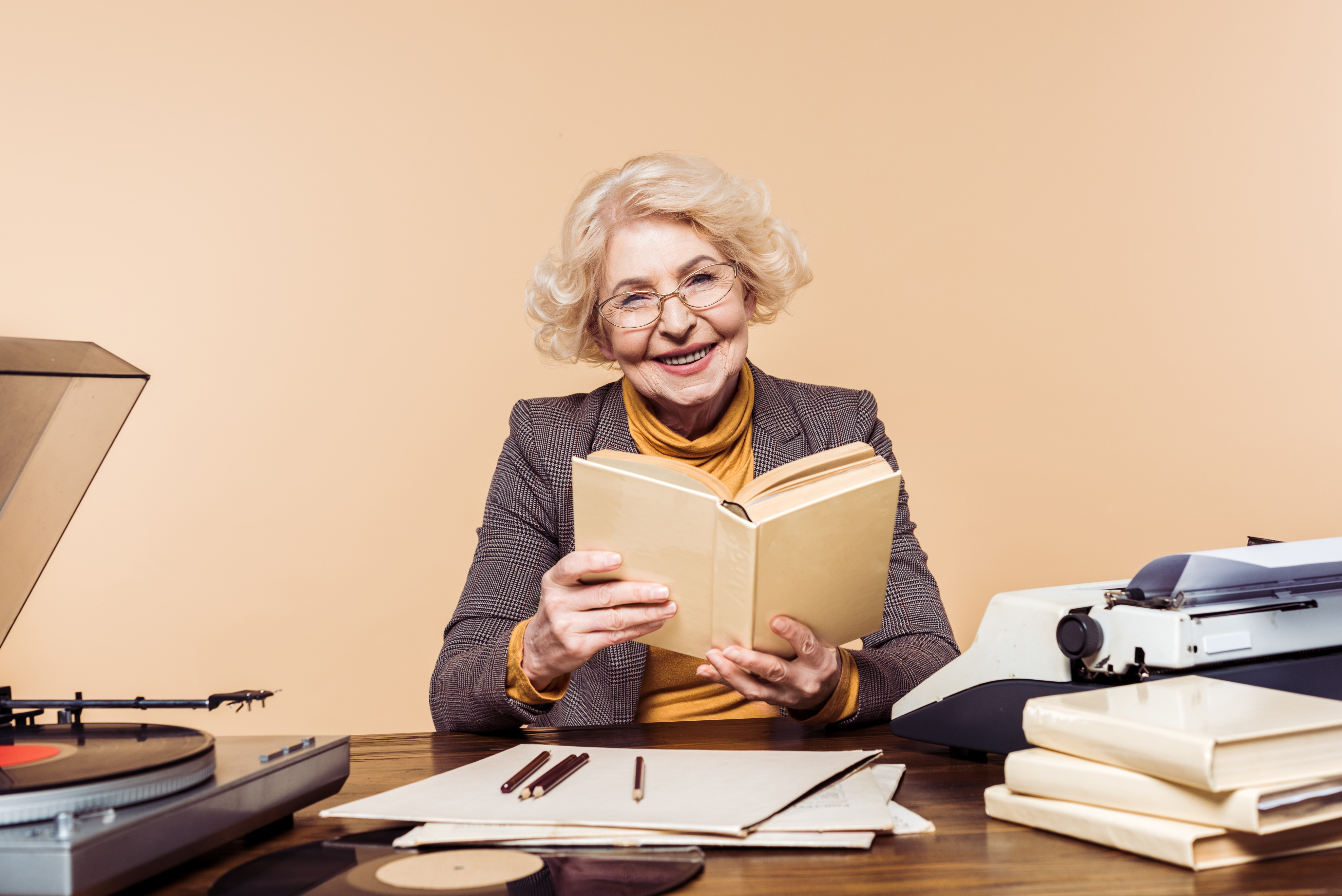 Author holding an open book in a warm office setting