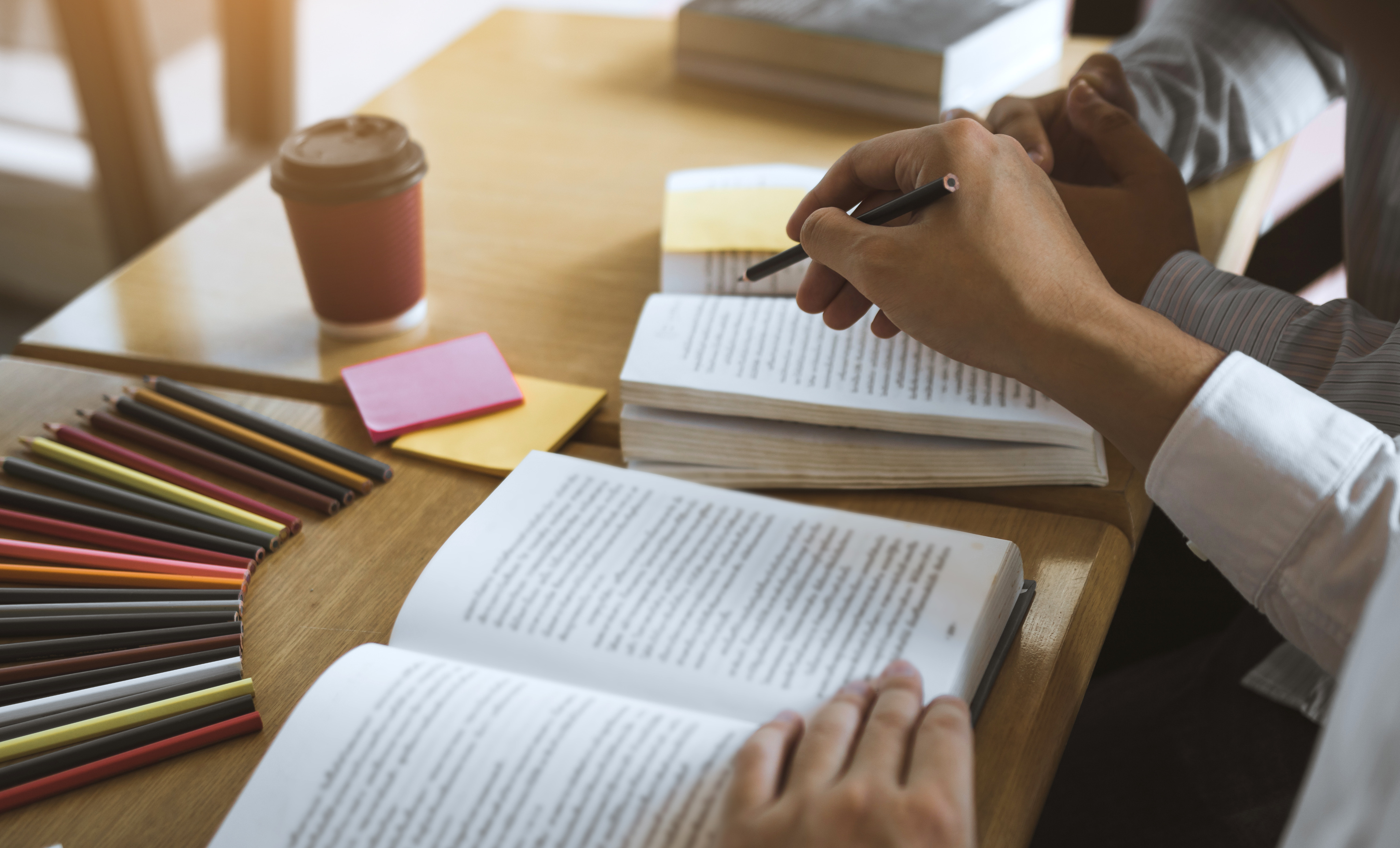 Editor reviewing a manuscript at a desk with colored pencils